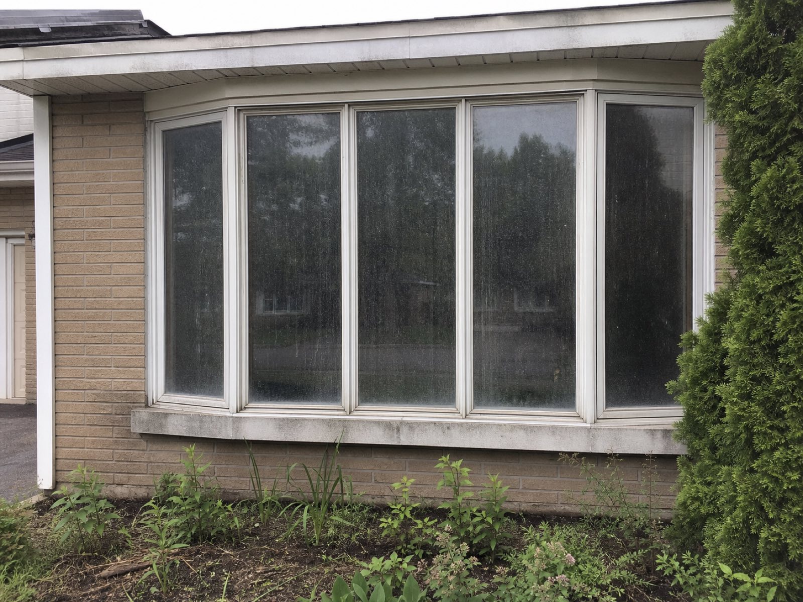 Wide bay window heavily spotted with rain and hard-water film before a Vonto Home Services cleaning